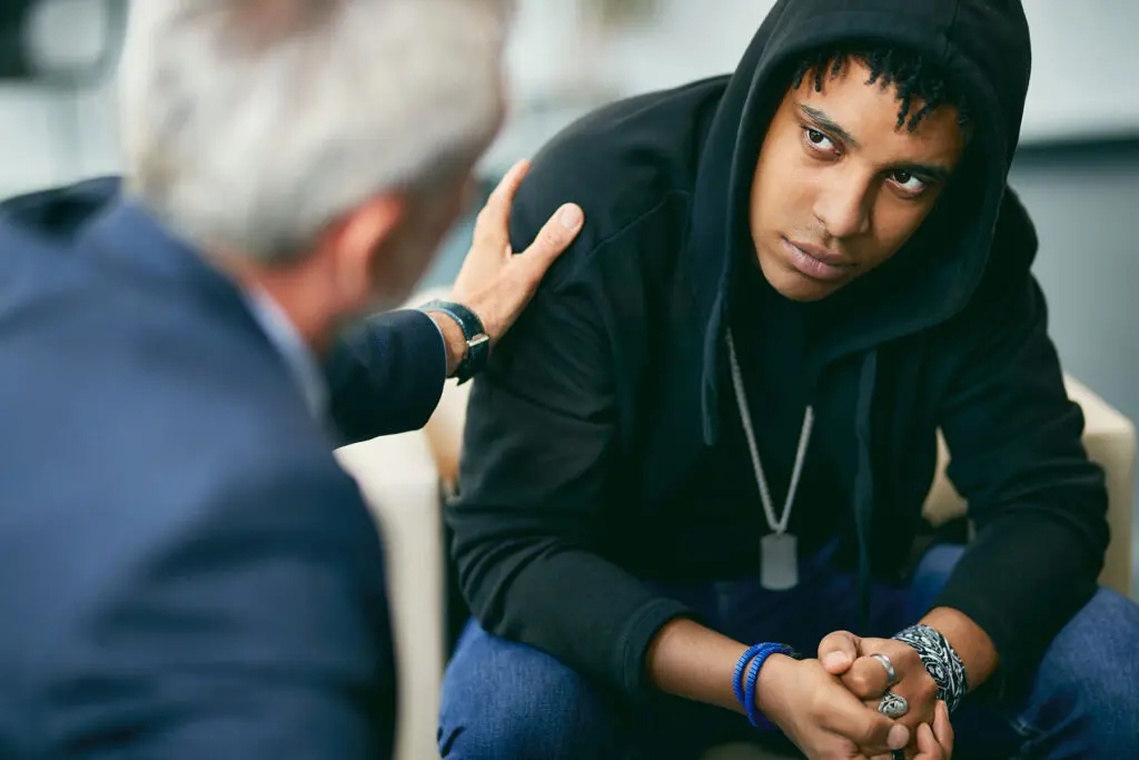 a teen in a hoodie talks to a therapist about treating bipolar disorder