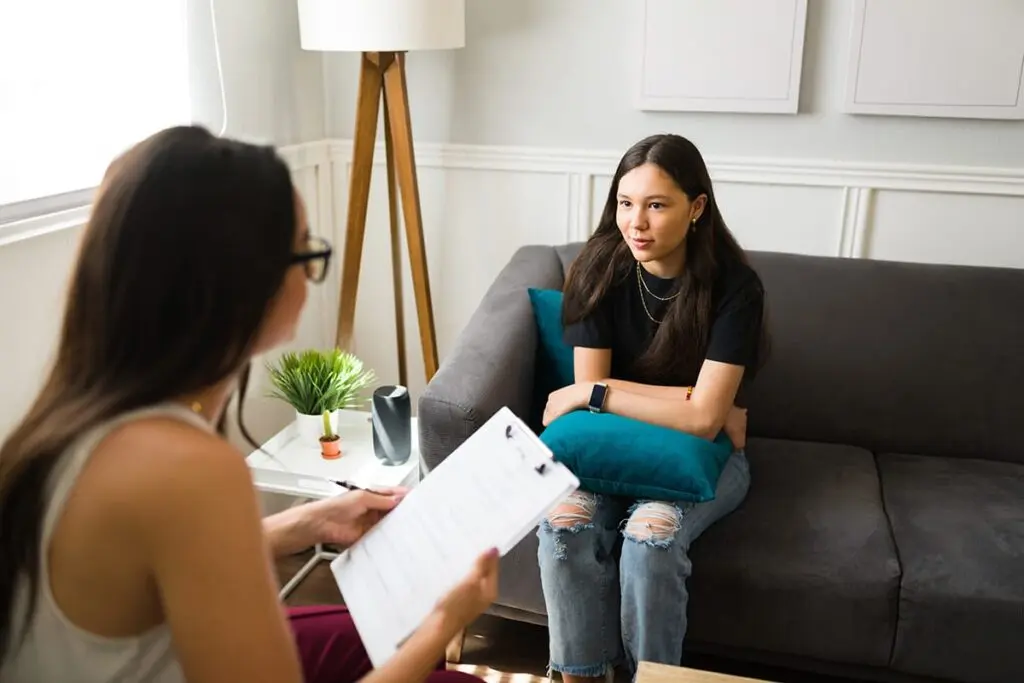a teen talks to a therapist during an adolescent day treatment program