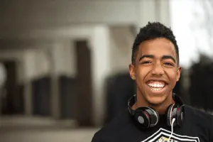 teenage boy smiling with headphones around his neck