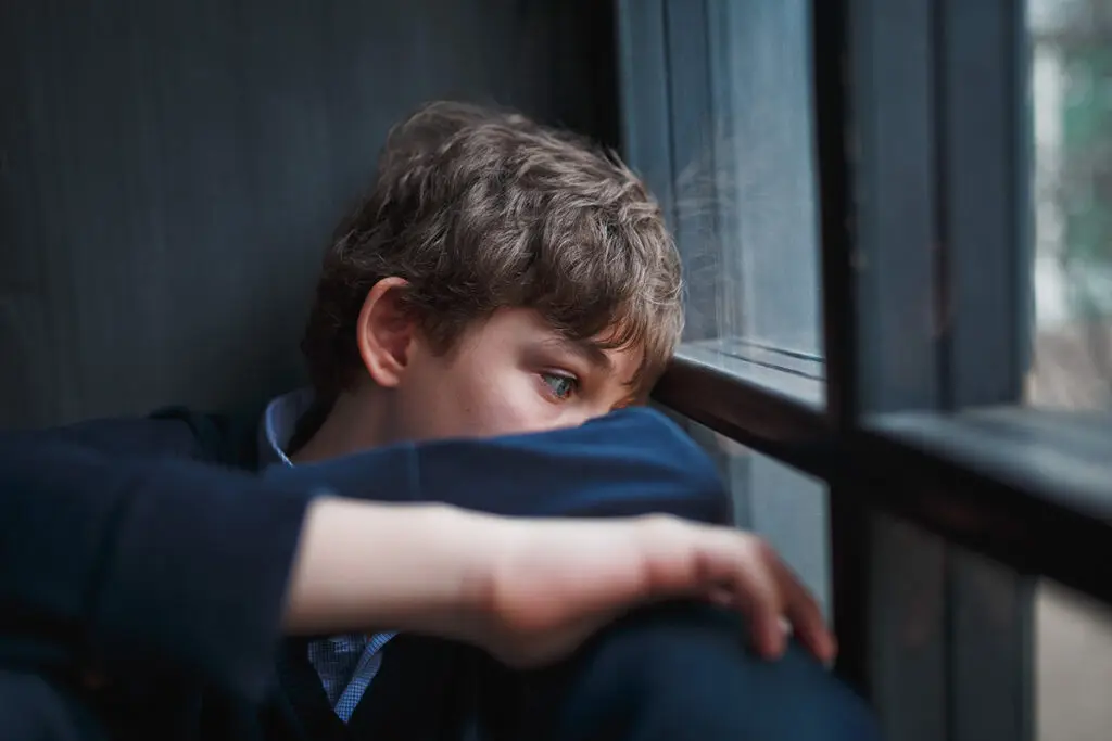 Teen leans against window and thinks about his unresolved trauma and addiction