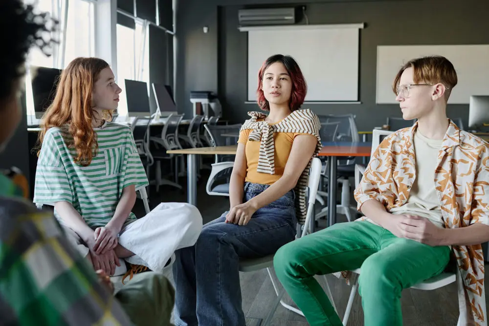 Teens participating in dual diagnosis group therapy led by a clinician at a mental health treatment center.