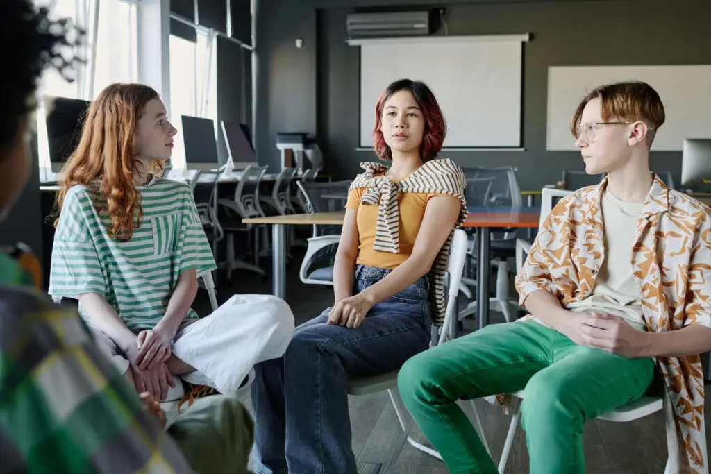 Teens participating in group therapy with a trauma-informed counselor for PTSD and addiction treatment in Massachusetts