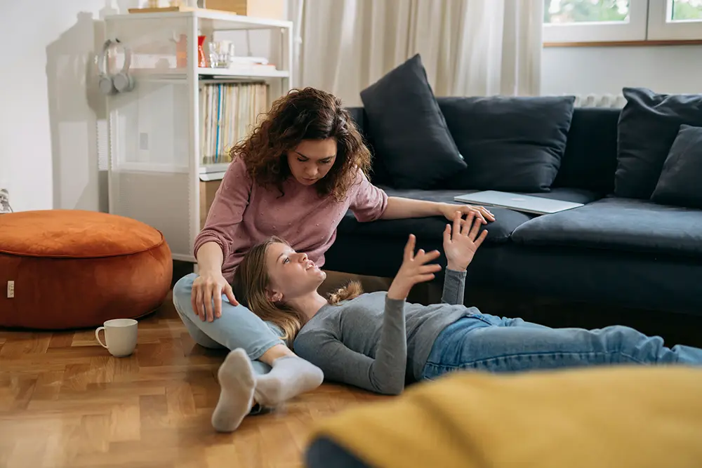 Parent gently talking to a teen on the floor, showing support and open communication about mental health