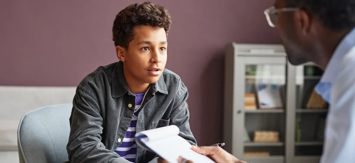 a teen talks to a therapist during behavioral disorder treatment