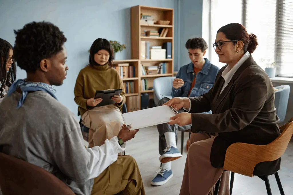 Diverse group of teens in therapy session with counselor promoting culturally sensitive teen mental health care.