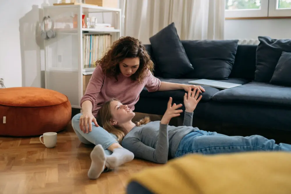 Parent sitting with teenager in the living room having a supportive conversation about emotions and mental health.