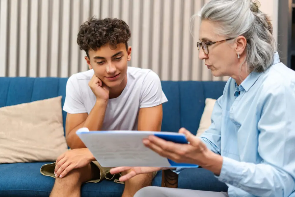 Teenage boy sitting in a therapy session with a counselor in a comfortable office setting.