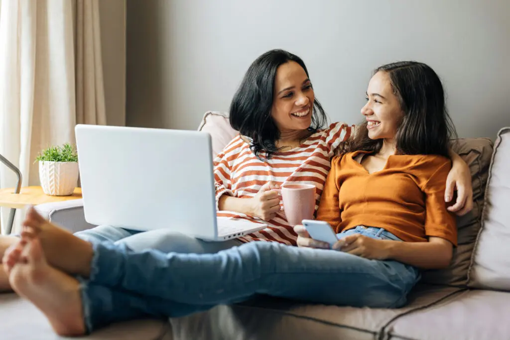 Mother researching trauma treatment with teen on bright chair.