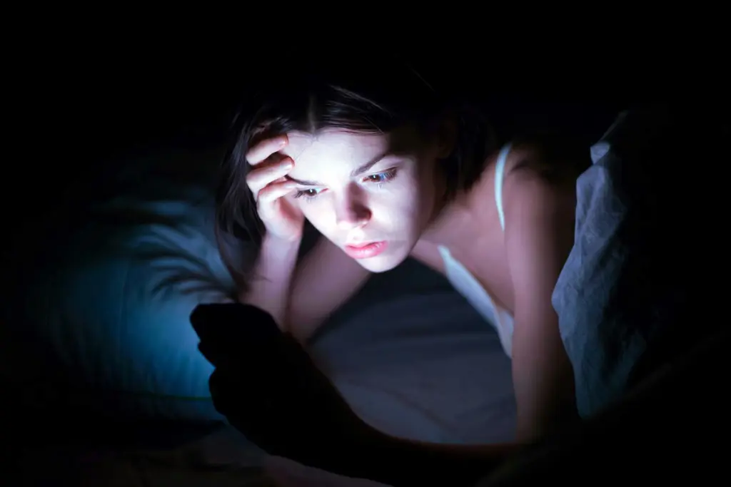 Teen using a smartphone late at night, reflecting the impact of AI and technology on teen mental health
