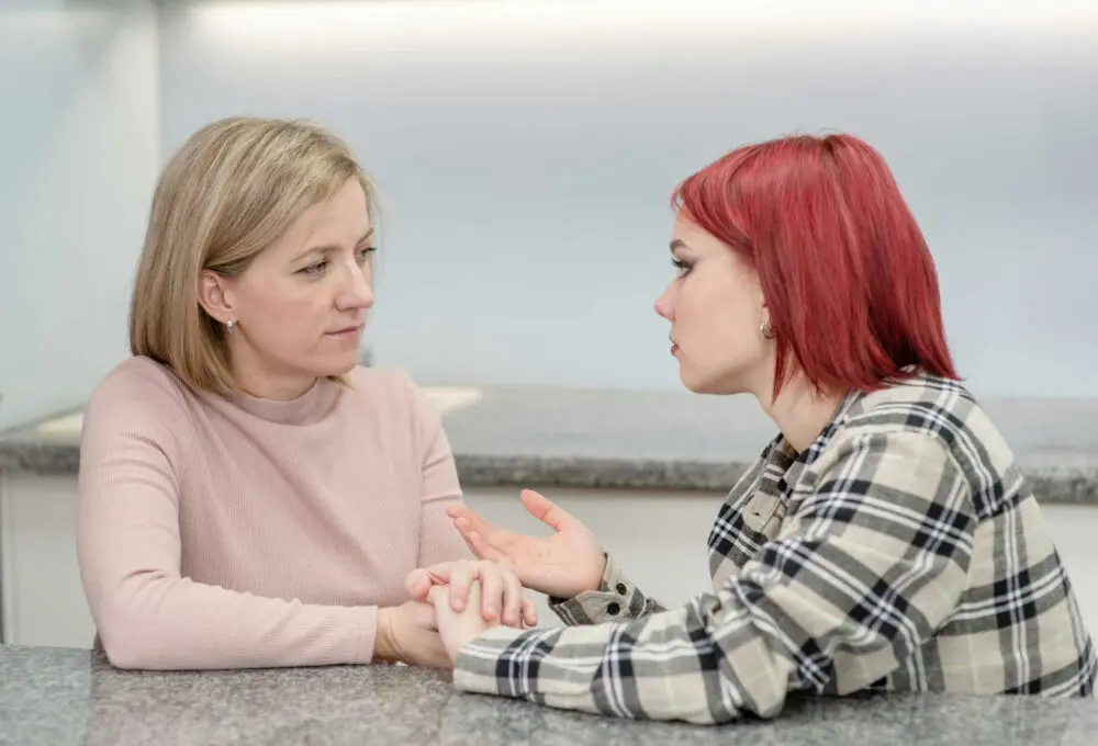Parent listening compassionately as their teenager talks about social anxiety in a comfortable home setting.