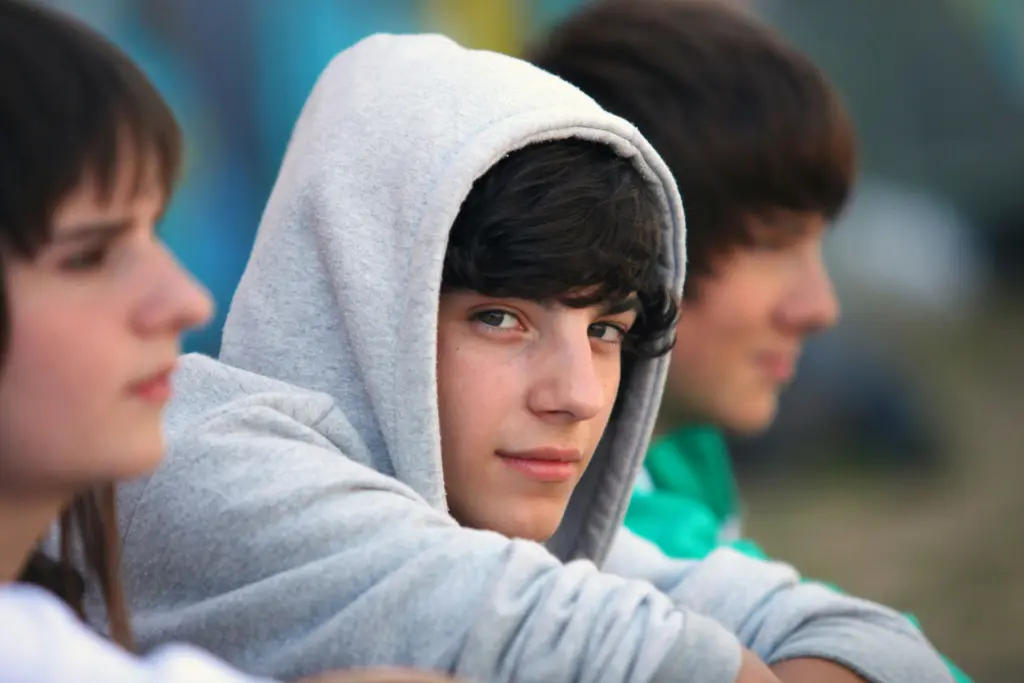 Teenage boy with ADHD and anxiety looking out from group.