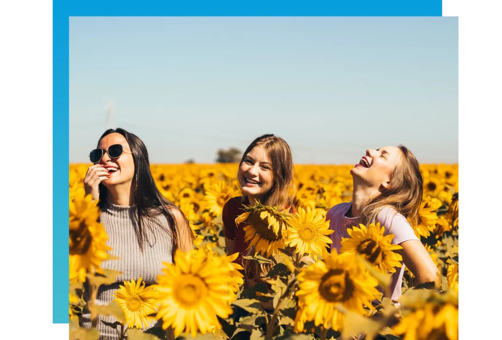 three young women in a sunflower field having fun