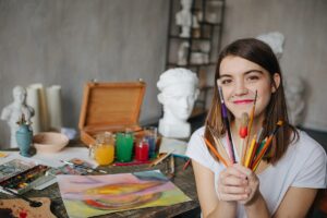 a teen looks happy to show off art supplies after learning art therapy ideas for teens