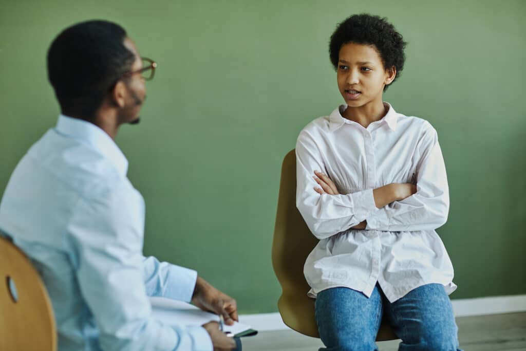 teen girl sitting with a therapist explaining her problems with social anxiety
