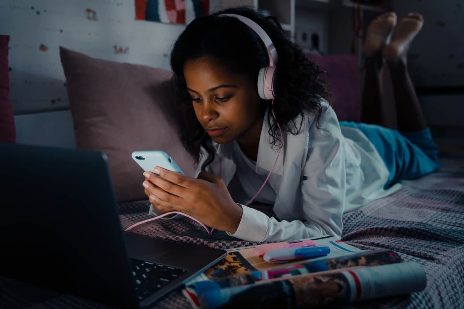 African teen girl in headphones scrolling social media