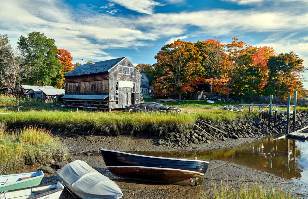 image of a shed on a body of water with a small boat in the foreground in essex massachsuetts