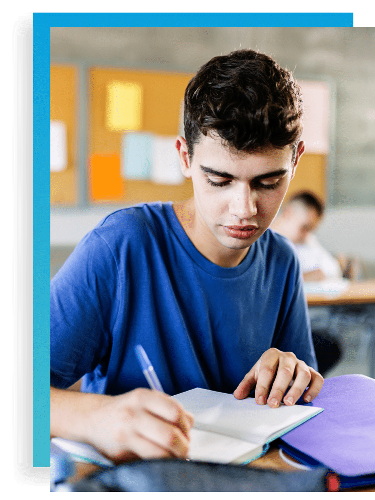 teen writing in his notebook at school at a desk