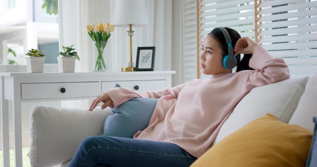 teen sitting on the couch with headphones decompressing from her OCD