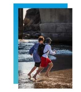 two teens run along the beach
