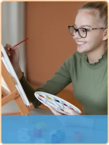 teen girl painting a picture while smiling