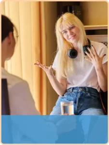 teen girl with blonde hair and headphones gestures to off-camera therapist