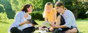 therapist speaks with teen girl and teen boy in an outdoor setting