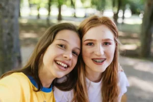 close-up of two teen girls smiling in outdoor setting