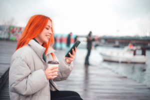 teen girl checking her phone on a boardwalk