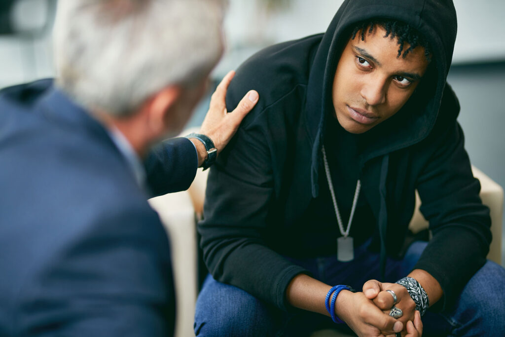 a teen in a hoodie talks to a therapist about treating bipolar disorder