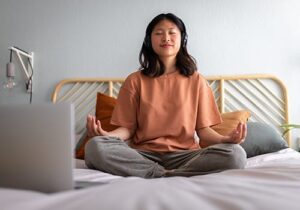 a teen meditates on their bed to show holistic therapy for mental health