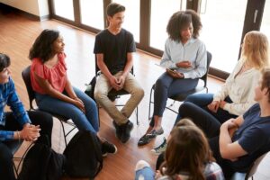 a group of teens sit in a circle during teen support groups