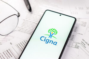 a pair of glasses and a phone on a table showing a logo for Cigna and cigna mental health coverage