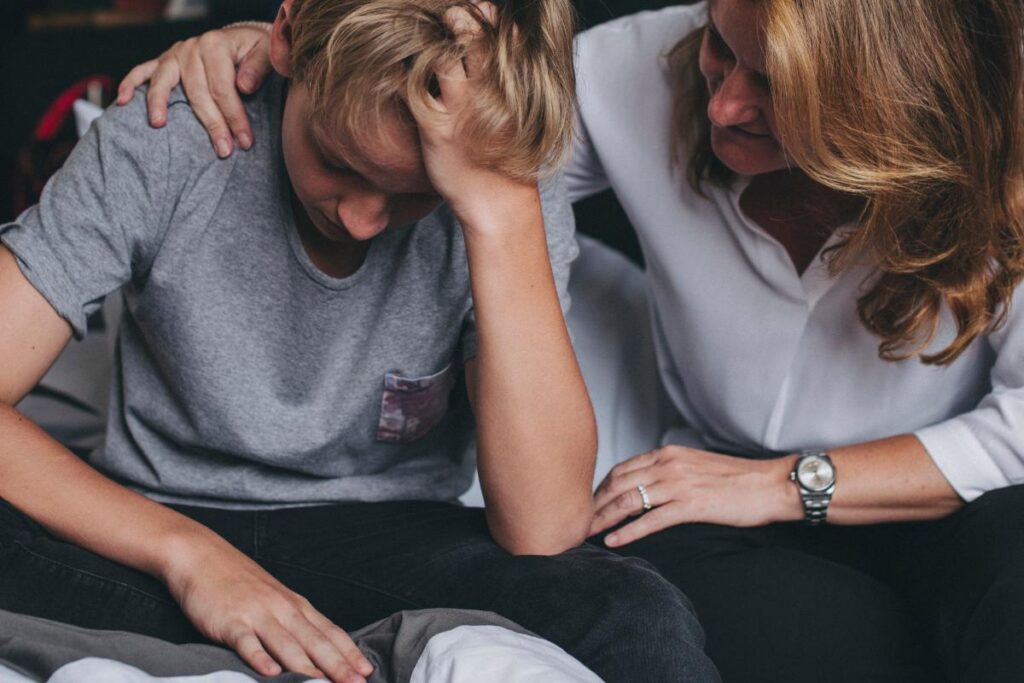 Woman puts arm around son as he struggles with a mental health emergency