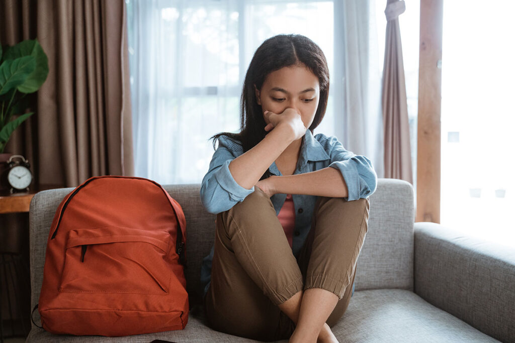 Woman sits on couch and worries if she has signs of attachment issues