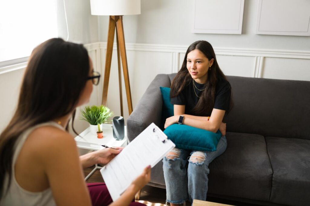 Teen sits on couch nervously and talks to therapist about a teen IOP