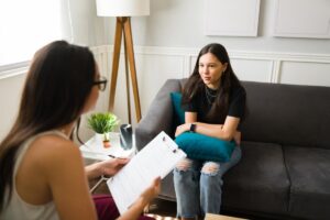 Teen sits on couch nervously and talks to therapist about a teen IOP