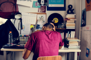 Teen sits at his desk, trying to write a paper while struggling with school stress