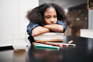 Girl puts head on book stack as she struggles with red flags in teenage behavior