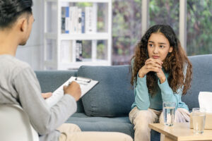 Teen sits on couch and listens to therapist talk about low self-esteem