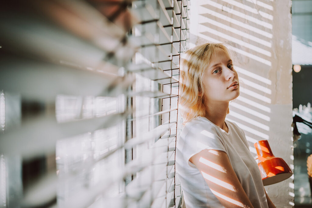 Woman leands on window while considering the best medication for OCD