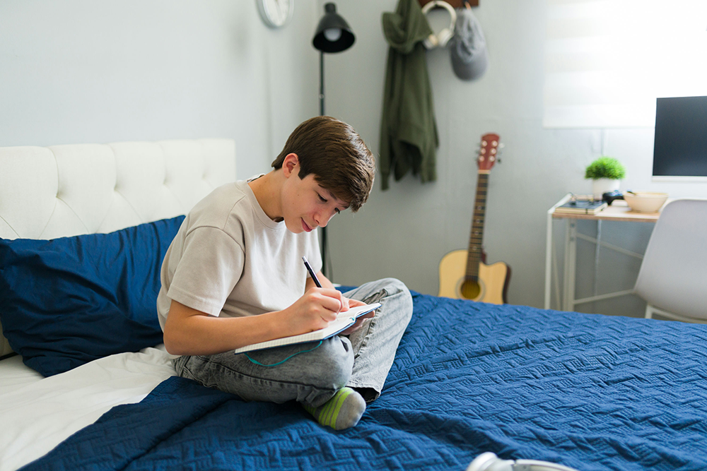 Teen writing down thoughts in a journal as part of a cognitive defusion exercise.