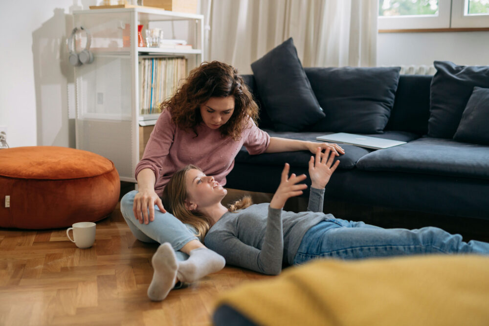 Parent sitting with teenager in the living room having a supportive conversation about emotions and mental health.