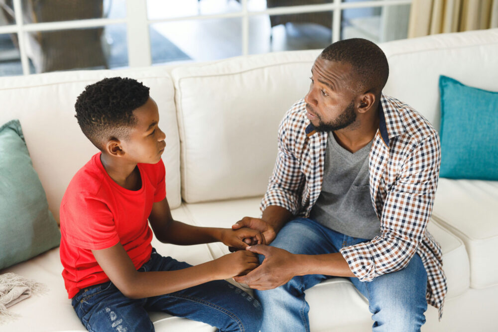 Parent talking with a struggling teenager at home while exploring mental health treatment options.