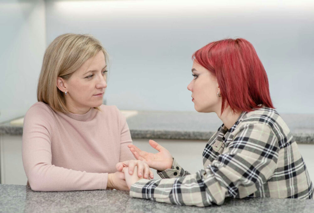 Parent listening compassionately as their teenager talks about social anxiety in a comfortable home setting.